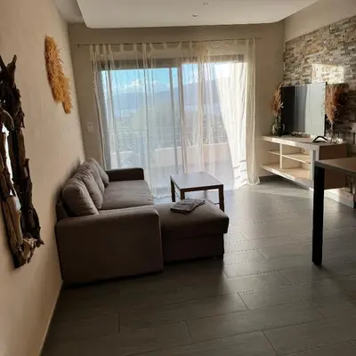 a living room with a couch and a large window at Appartemment vue mer 50m2 in Propriano