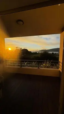 a view of a sunset through a window on a balcony at Appartemment vue mer 50m2 in Propriano