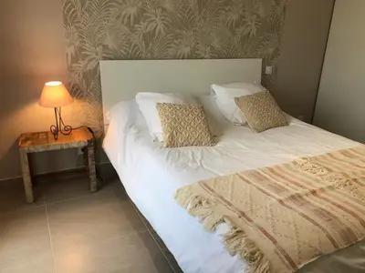 a bed with white sheets and pillows next to a table at PDM Appartement Paese di Mare in Santa-Lucia-di-Moriani