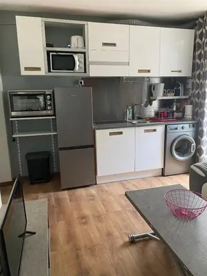 a small kitchen with white cabinets and a table at OTA T2 proche rivières et plages, randonnées in Guaita