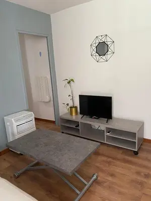 a living room with a tv and a table at OTA T2 proche rivières et plages, randonnées in Guaita