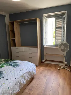 a bedroom with a bed and a dresser and a fan at OTA T2 proche rivières et plages, randonnées in Guaita