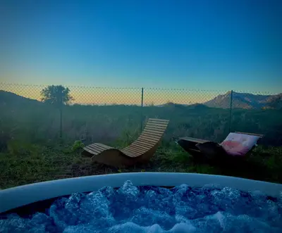 a hot tub with a view of a chair and mountains at T3 Baie de Calvi jardin panoramique vue mer in Calenzana