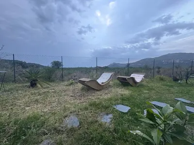 two lounge chairs sitting in the grass near a fence at T3 Baie de Calvi jardin panoramique vue mer in Calenzana