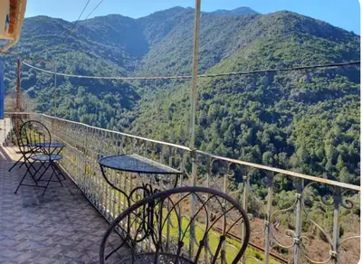 a table and chairs on a balcony with a view of mountains at Appartement Caprunale Rivière & Maquis in Manso