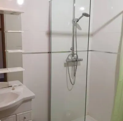 a shower with a glass door next to a sink at Appartement Caprunale Rivière & Maquis in Manso