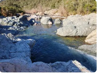 a river with some rocks and blue water at Appartement Caprunale Rivière & Maquis in Manso