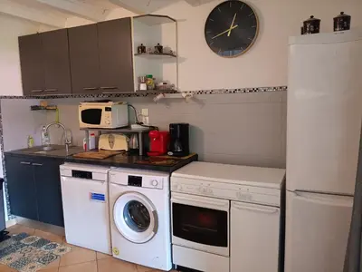 a kitchen with a washing machine and a clock on the wall at Corse-San Giuliano-maison- 2 mn de la plage in San-Giuliano