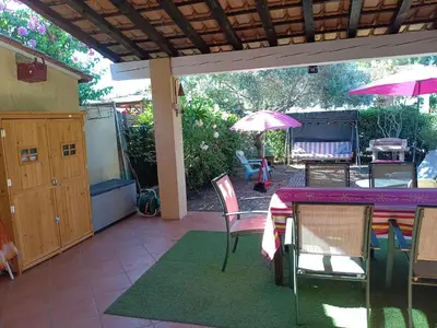 a patio with a table and chairs and an umbrella at Corse-San Giuliano-maison- 2 mn de la plage in San-Giuliano