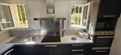 a kitchen with a stove and a sink and two windows at T3 Dolce & Vita A3 avec Piscine et vue Montagnes in Propriano