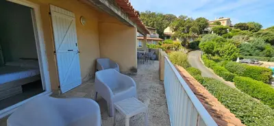 a balcony with a bed and chairs on a house at T3 Dolce & Vita A3 avec Piscine et vue Montagnes in Propriano