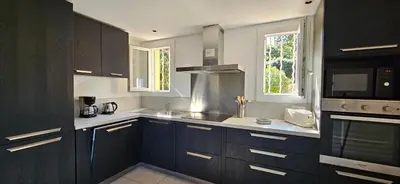 a kitchen with dark wood cabinets and a microwave at T3 Dolce & Vita A3 avec Piscine et vue Montagnes in Propriano