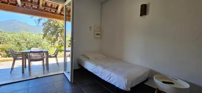 a room with a bed and a table and a balcony at Studio Dolce & Vita C2 vue mer avec piscine in Propriano
