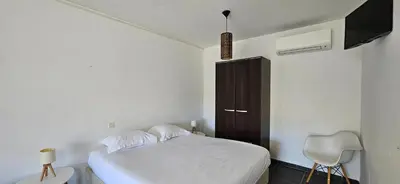 a bedroom with a white bed and a chair at Studio Dolce & Vita C2 vue mer avec piscine in Propriano