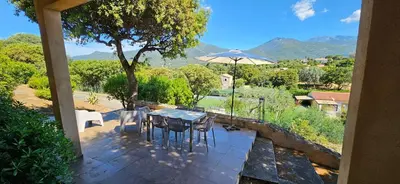 a patio with a table and chairs and an umbrella at T3 Dolce & Vita D5 avec Piscine et vue Montagnes in Propriano