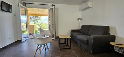 a living room with a couch and a table at T3 Dolce & Vita D5 avec Piscine et vue Montagnes in Propriano
