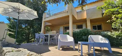 a table and chairs and an umbrella in front of a house at T3 Dolce & Vita D5 avec Piscine et vue Montagnes in Propriano