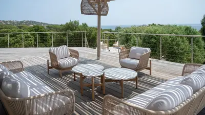 a deck with chairs and a table and chairs at Villa avec piscine et vue mer à 230m de la plage in Zonza