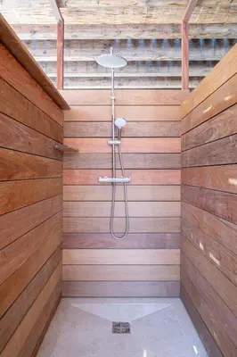 a shower in a bathroom with wooden walls at Villa avec piscine et vue mer à 230m de la plage in Zonza