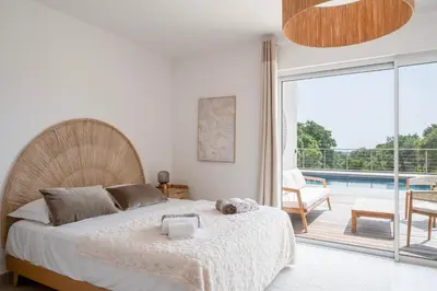 a bedroom with a bed and a balcony with a pool at Villa avec piscine et vue mer à 230m de la plage in Zonza