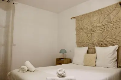 a bedroom with a white bed with a large headboard at Les Hauts du Port-appartement élégant et central in Bonifacio