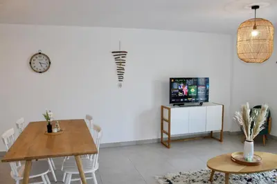 a dining room with a table and a tv at Les Hauts du Port-appartement élégant et central in Bonifacio