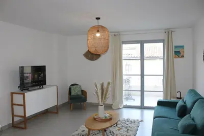 a living room with a blue couch and a tv at Les Hauts du Port-appartement élégant et central in Bonifacio