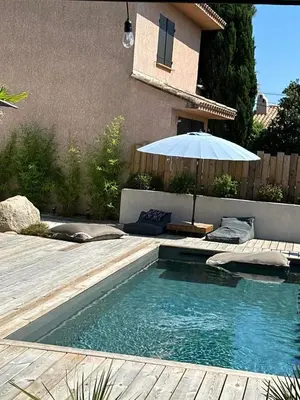 a swimming pool with an umbrella next to a house at Villa Saint-Cyprien Corse in Lecci
