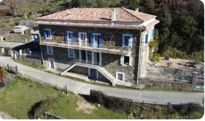 a large house with blue windows on a hill at Appartement Saltare Rivière & maquis in Manso