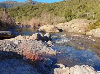 a river with rocks and mountains in the background at Appartement Saltare Rivière & maquis in Manso