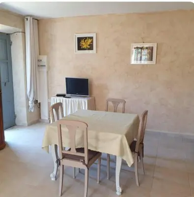 a dining room with a table and chairs and a television at Appartement Saltare Rivière & maquis in Manso