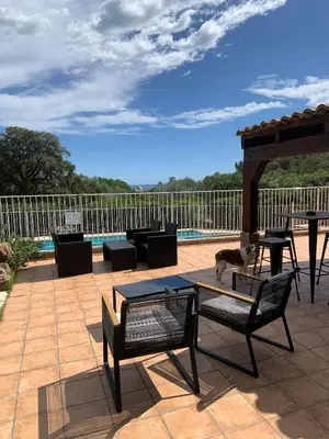 a dog standing on a patio with a table and chairs at Résidence U LATONU in Porto-Vecchio