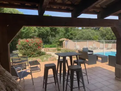 a patio with a table and chairs and a pool at Résidence U LATONU in Porto-Vecchio