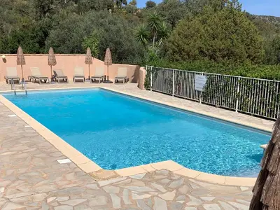 a swimming pool with chairs and a fence at Résidence U LATONU in Porto-Vecchio