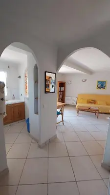 a living room with an archway and a yellow couch at 2 pièces accès direct plage in Sainte-Lucie de Porto-Vecchio