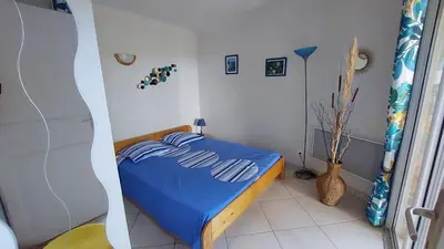 a bedroom with a blue bed in a room at 2 pièces accès direct plage in Sainte-Lucie de Porto-Vecchio