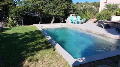 a swimming pool with two blue chairs in a yard at 2 pièces accès direct plage in Sainte-Lucie de Porto-Vecchio