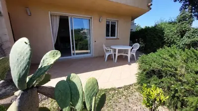 a patio with a table and chairs and a cactus at 2 pièces accès direct plage in Sainte-Lucie de Porto-Vecchio