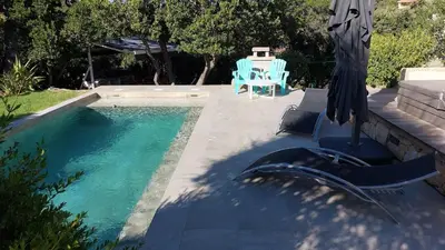 a swimming pool with an umbrella and a table and chairs at 2 pièces accès direct plage in Sainte-Lucie de Porto-Vecchio