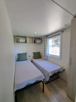 two beds in a small room with a window at chalet 3 au cœur du maquis in Bonifacio