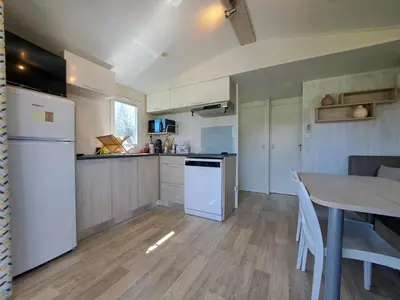 a kitchen with a table and a white refrigerator at chalet 3 au cœur du maquis in Bonifacio