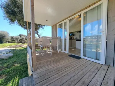 a screened porch with a table and chairs on a house at chalet 3 au cœur du maquis in Bonifacio