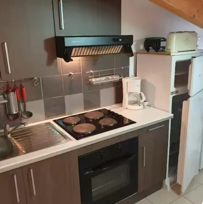 a kitchen with a stove top oven next to a refrigerator at Appartement Paglia Orba Rivière & maquis in Manso