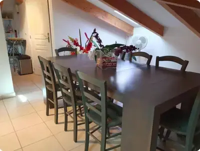 a dining room table with chairs and a table with flowers at Appartement Paglia Orba Rivière & maquis in Manso