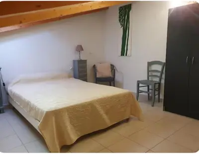 a bedroom with a bed and a table and chairs at Appartement Paglia Orba Rivière & maquis in Manso