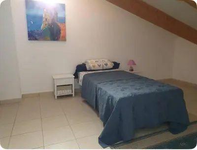 a bedroom with a bed with a blue bedspread at Appartement Paglia Orba Rivière & maquis in Manso