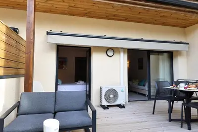 a patio with a couch and a fan on a deck at U Speronu - Plage Privée & Piscine Chauffée in Pianottoli-Caldarello