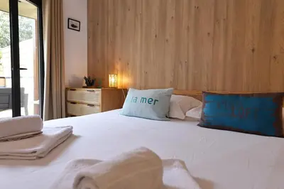 a bedroom with a large white bed with two pillows at U Speronu - Plage Privée & Piscine Chauffée in Pianottoli-Caldarello