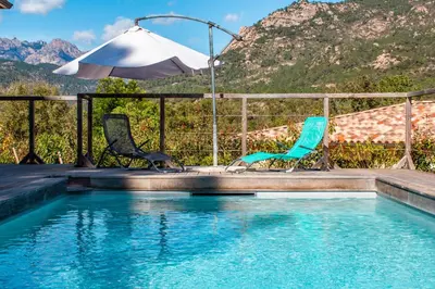 two chairs and an umbrella next to a swimming pool at Casa Cavu di Santa Lucia in Sainte-Lucie de Porto-Vecchio