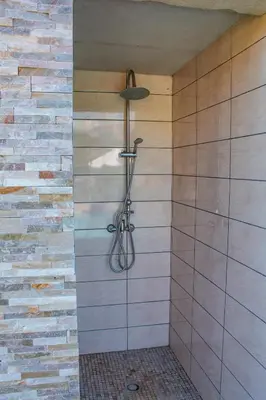 a shower in a bathroom with a brick wall at Casa Cavu di Santa Lucia in Sainte-Lucie de Porto-Vecchio